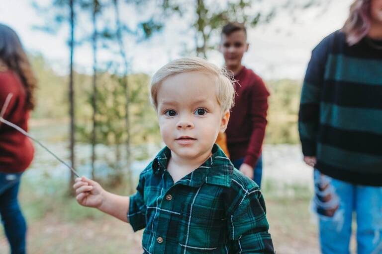 little boy holding stick in woods