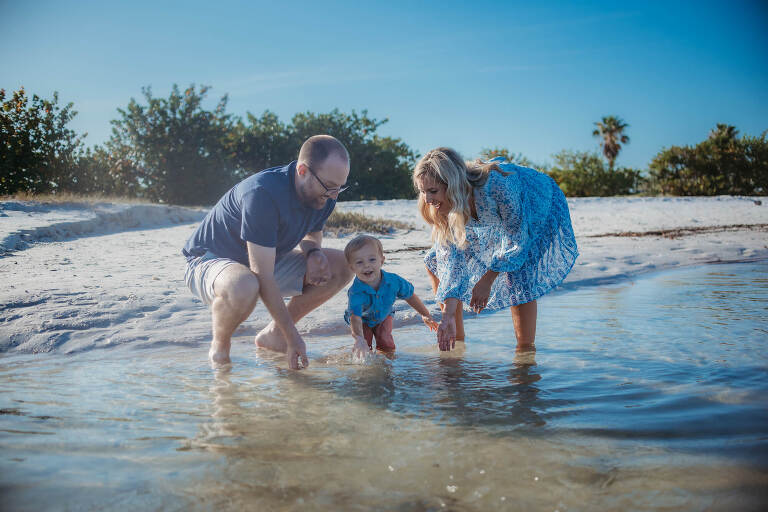 mom and dad playing with little boy splashing in the water