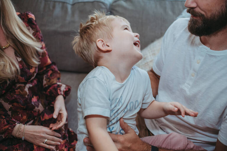 little boy laughing with his parents