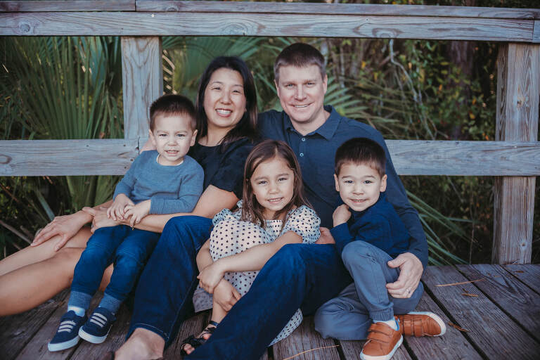 family sitting together on wooden bridge