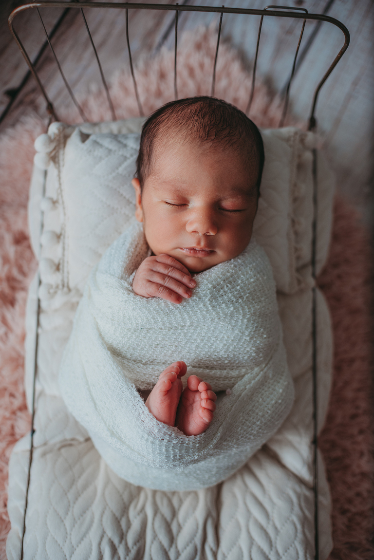 newborn baby girl all wrapped up in wire bed