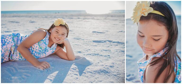 little girl laying in the beach sand