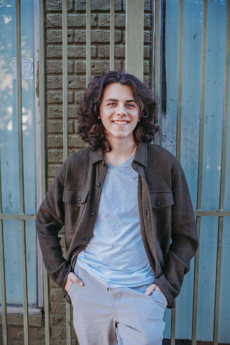 senior boy smiles leaning against grate in downtown Tampa senior photos