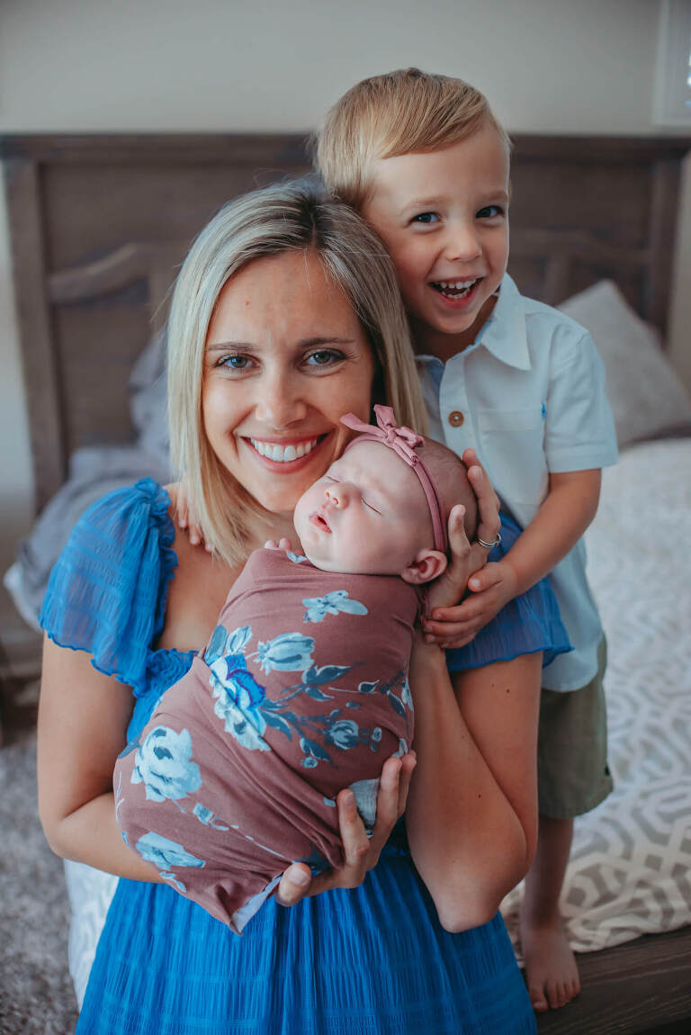 mom holding new baby girl with older son